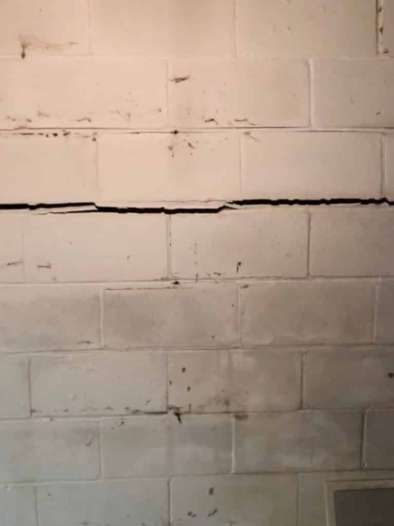 Very cracked and bowed inwards brick wall