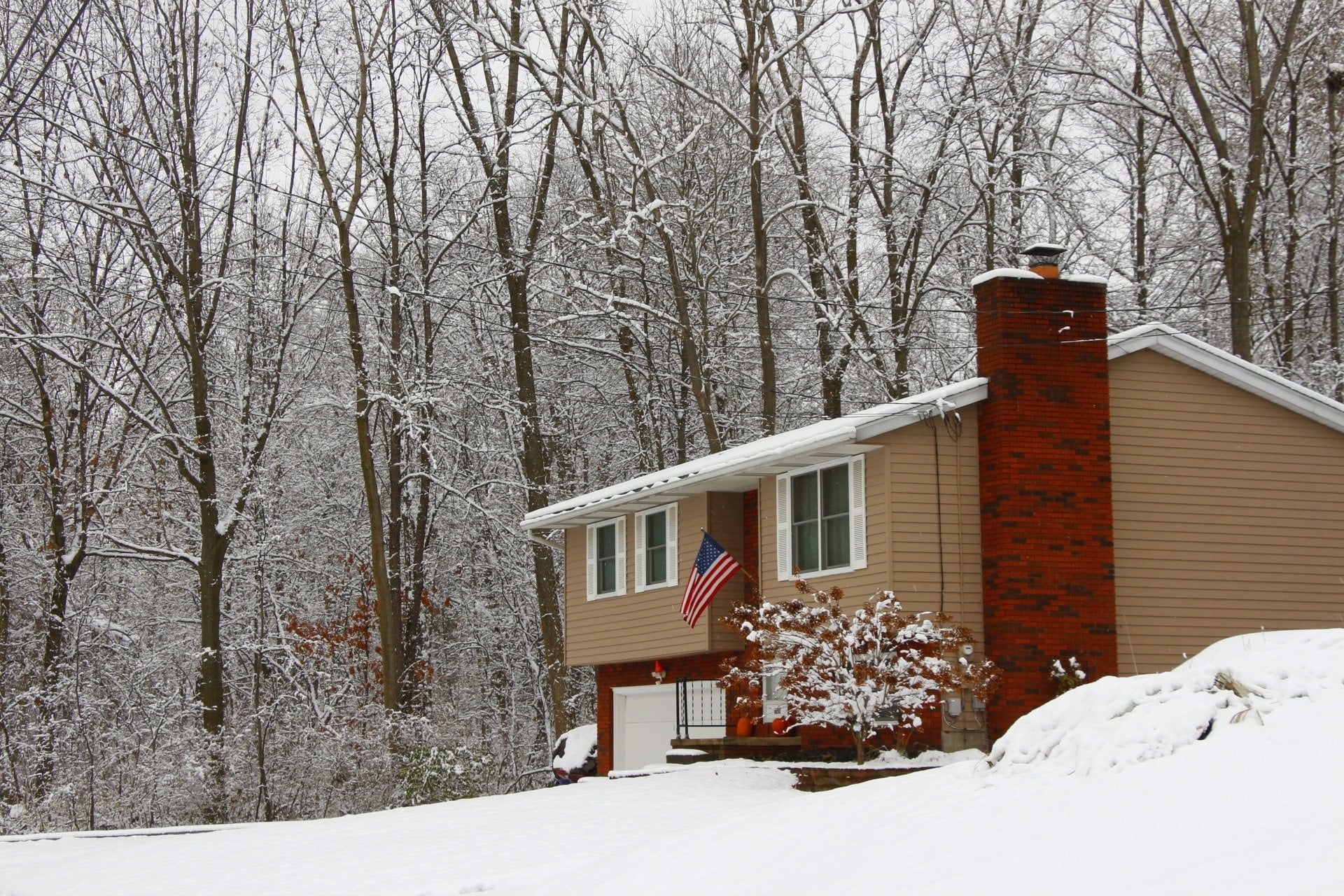House in woods in winter covered in snow